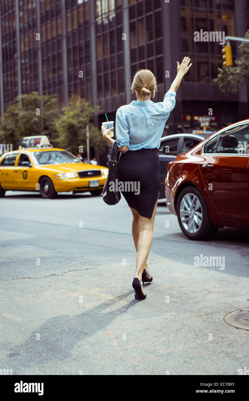 Kaukasische Frau hagelt Taxi in städtischen Straße Stockfoto