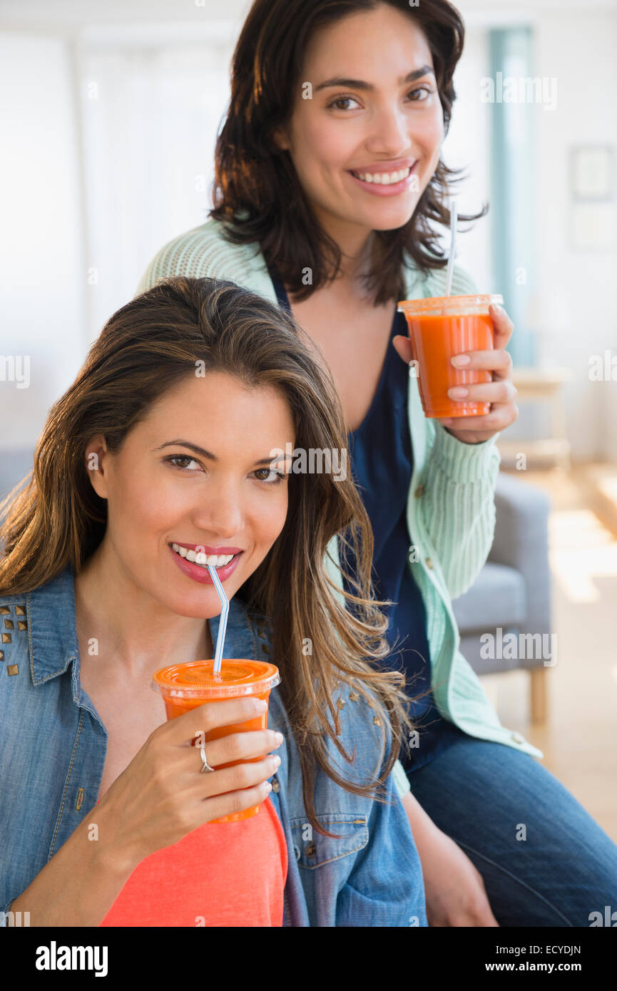 Hispanische Frauen trinken gesunde Karotten-Saft im Wohnzimmer Stockfoto