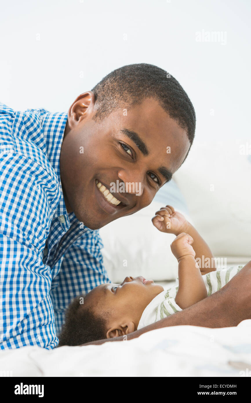 Vater lächelnd mit Baby Sohn auf Bett Stockfoto