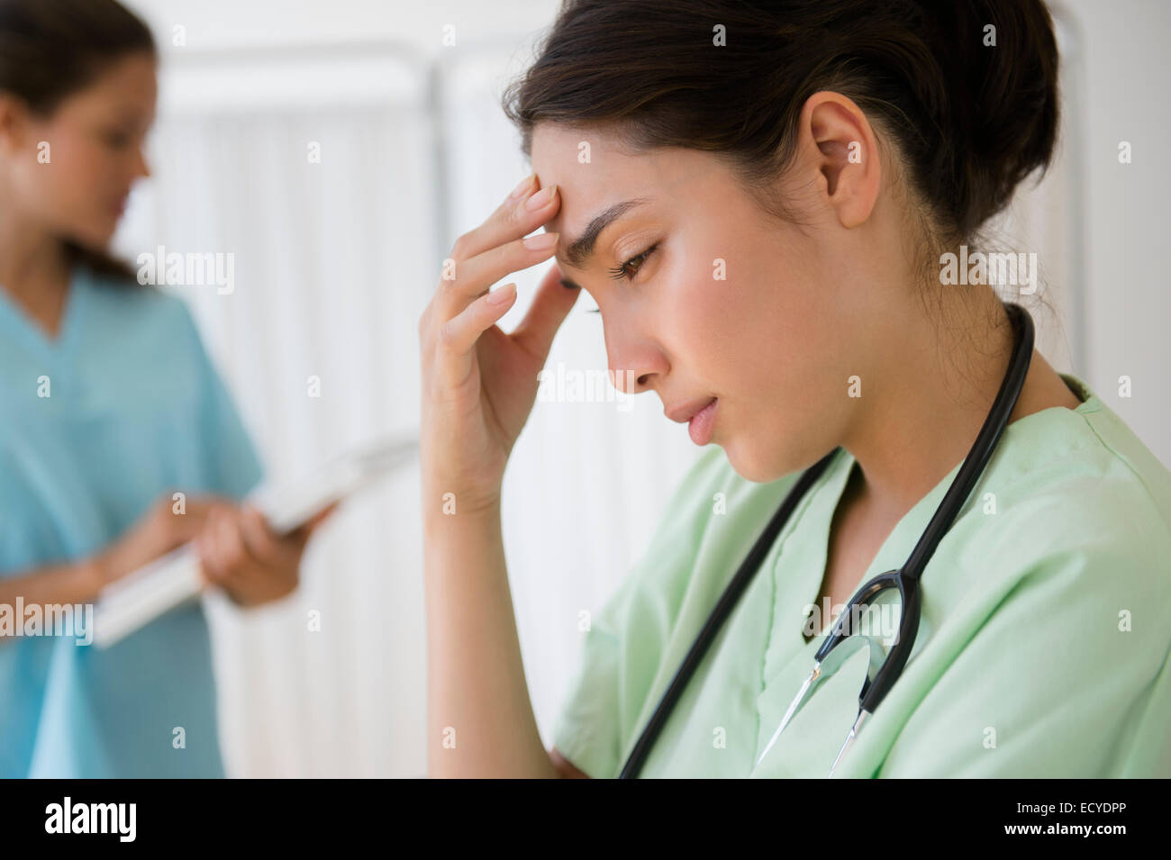 Hispanische Krankenschwester reiben Stirn im Krankenhaus Stockfoto