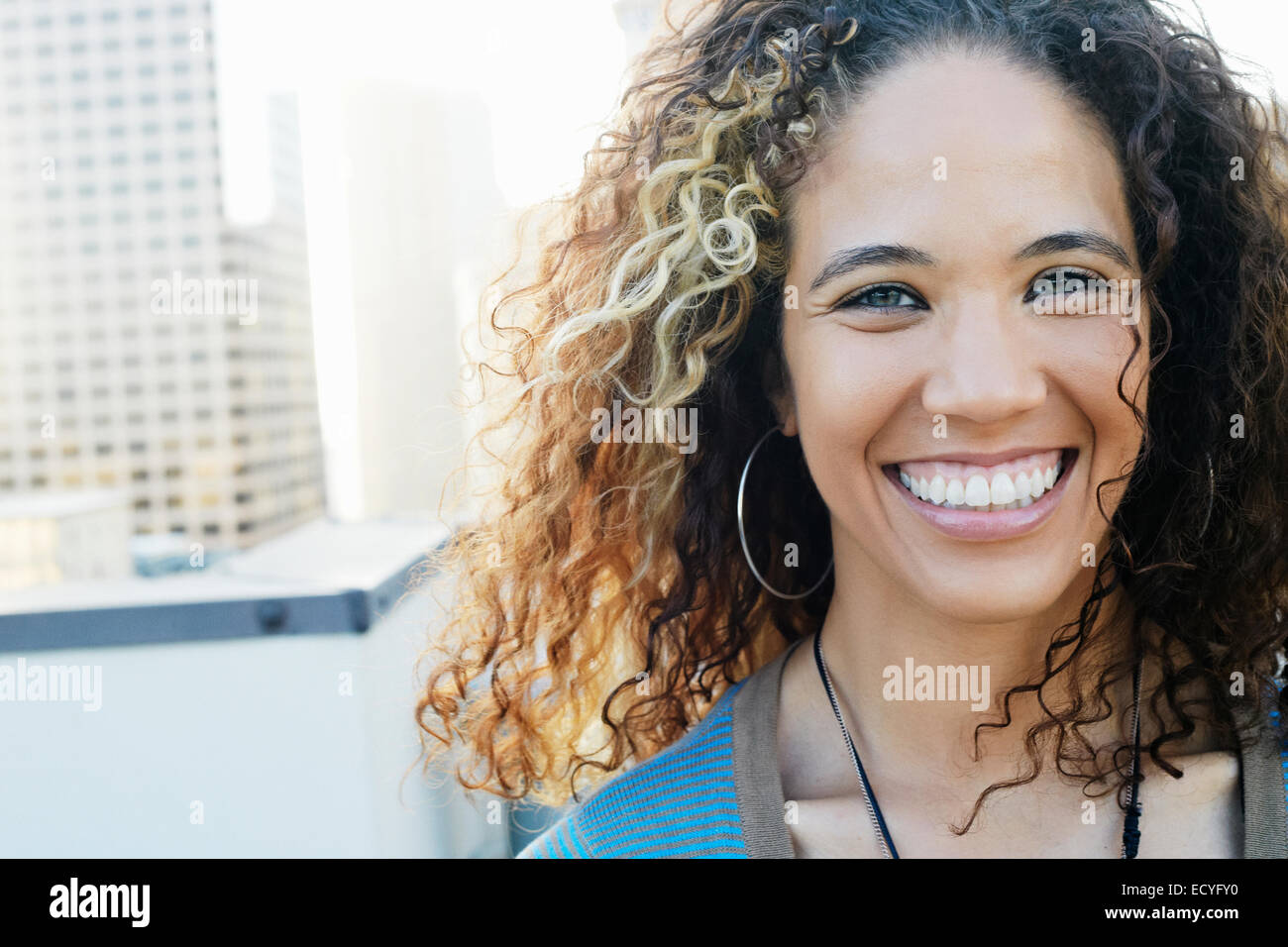 Gemischte Rassen Frau lächelnd auf städtischen Dach Stockfoto
