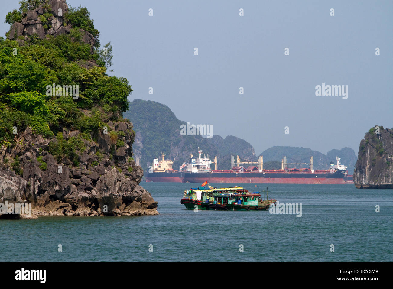 Hausboote und Containerschiffe in Ha Long Bucht, Vietnam. Stockfoto