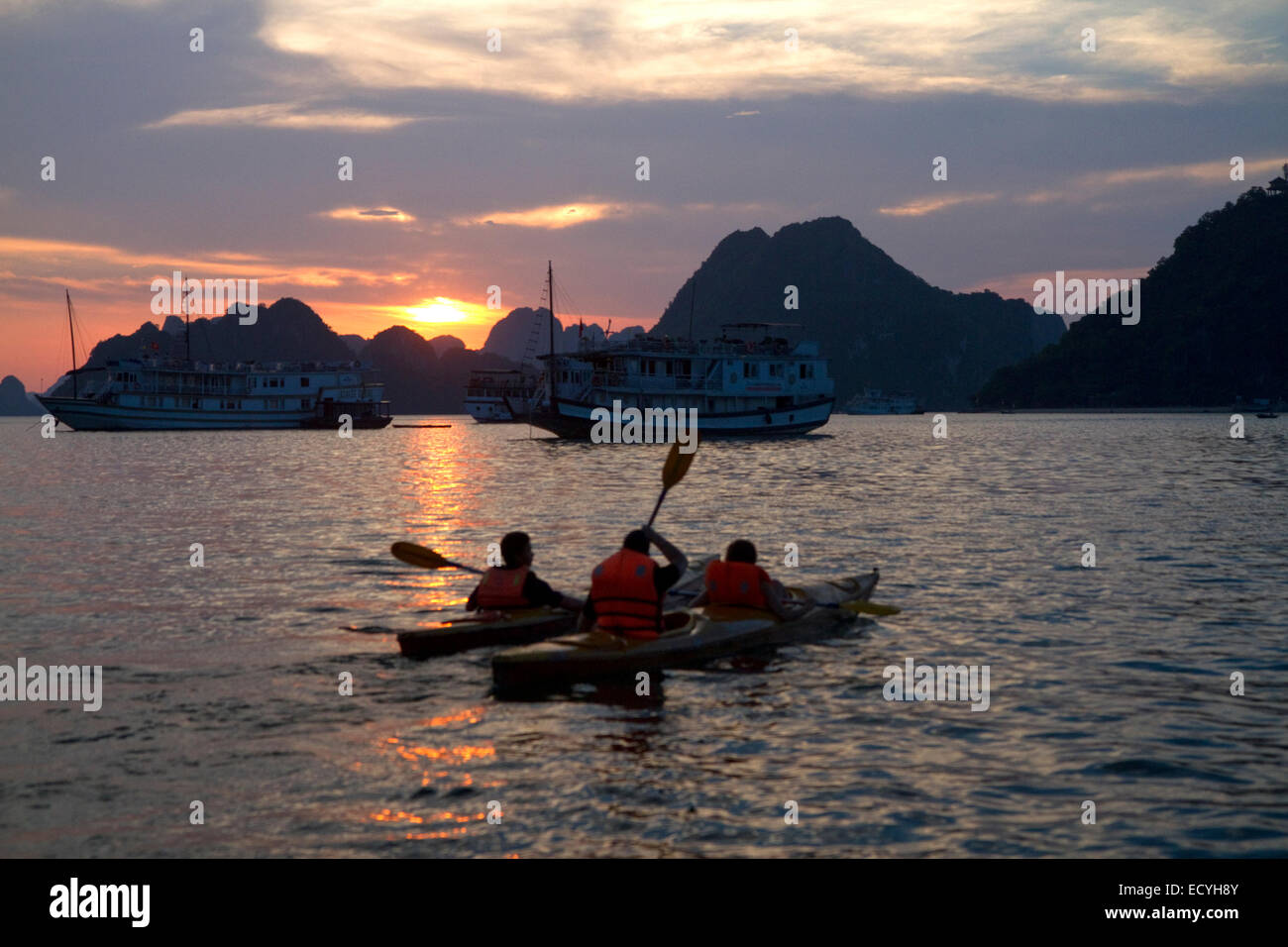 Touristen mit Seekajaks bei Sonnenuntergang in Ha Long Bucht, Vietnam. Stockfoto