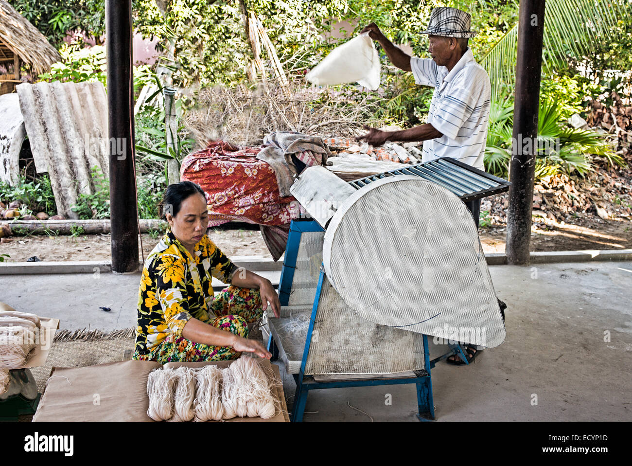 Mann und Frau läuft eine Nudel-Schneidemaschine in ihrer kleinen Heimat Reispapier und Nudelfabrik.  Der Mann ernährt das Reispapier in die Maschine und die Frau fängt und Pakete die Nudeln, wie sie geschnitten sind. Stockfoto