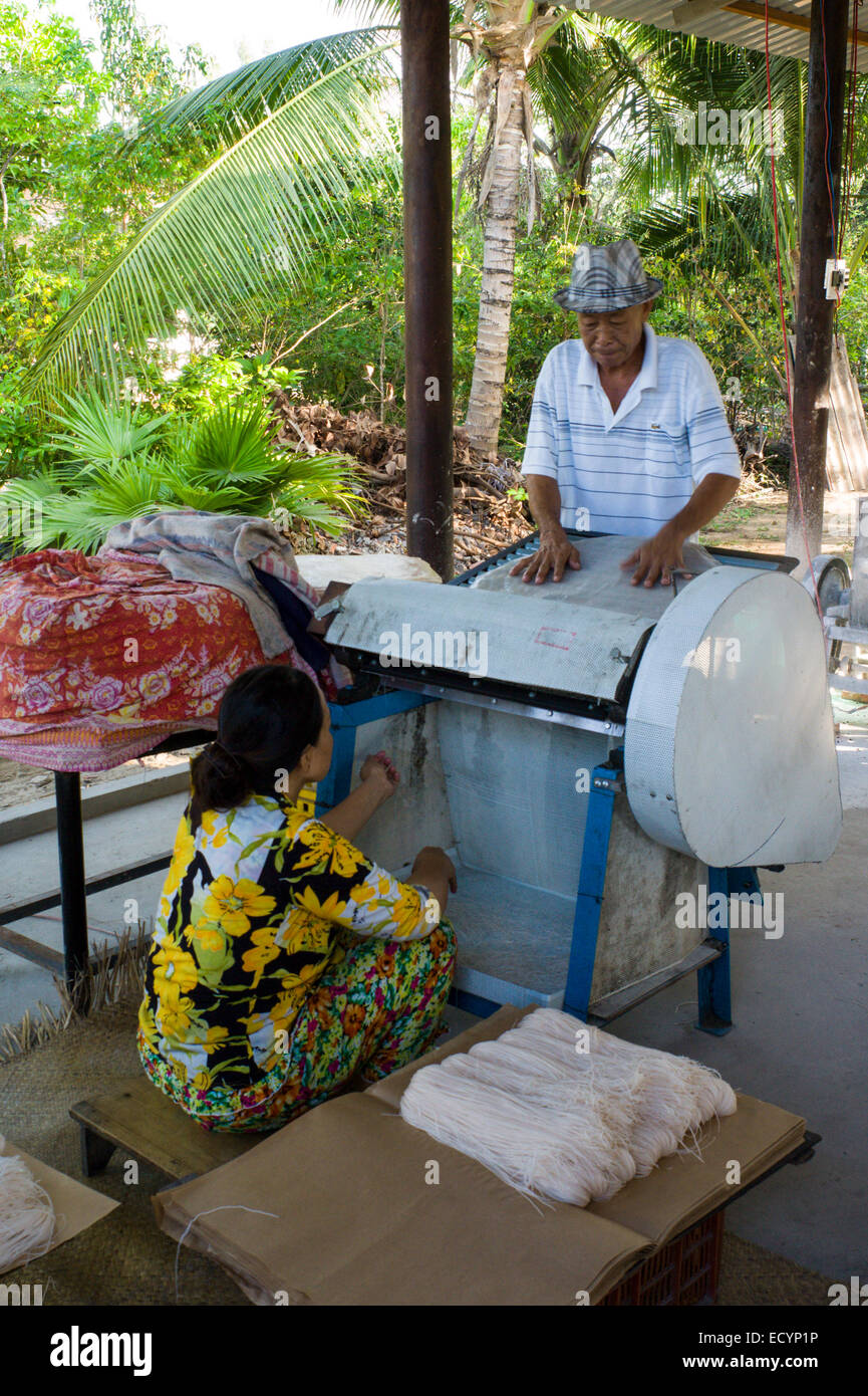 Vater der Familie ernährt Reis Papier in einem Nudel-Cutter als seine Frau Fänge und Pakete, die der Schnitt in ihrer Heimat Reispapier und Nudelfabrik Nudeln. Stockfoto
