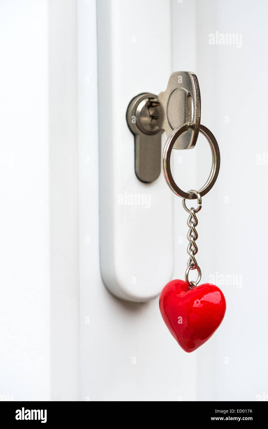 Schlüssel eingesteckt ein Türschloss mit einem Schlüsselring in Form eines Herzens - hell erleuchtet Stockfoto