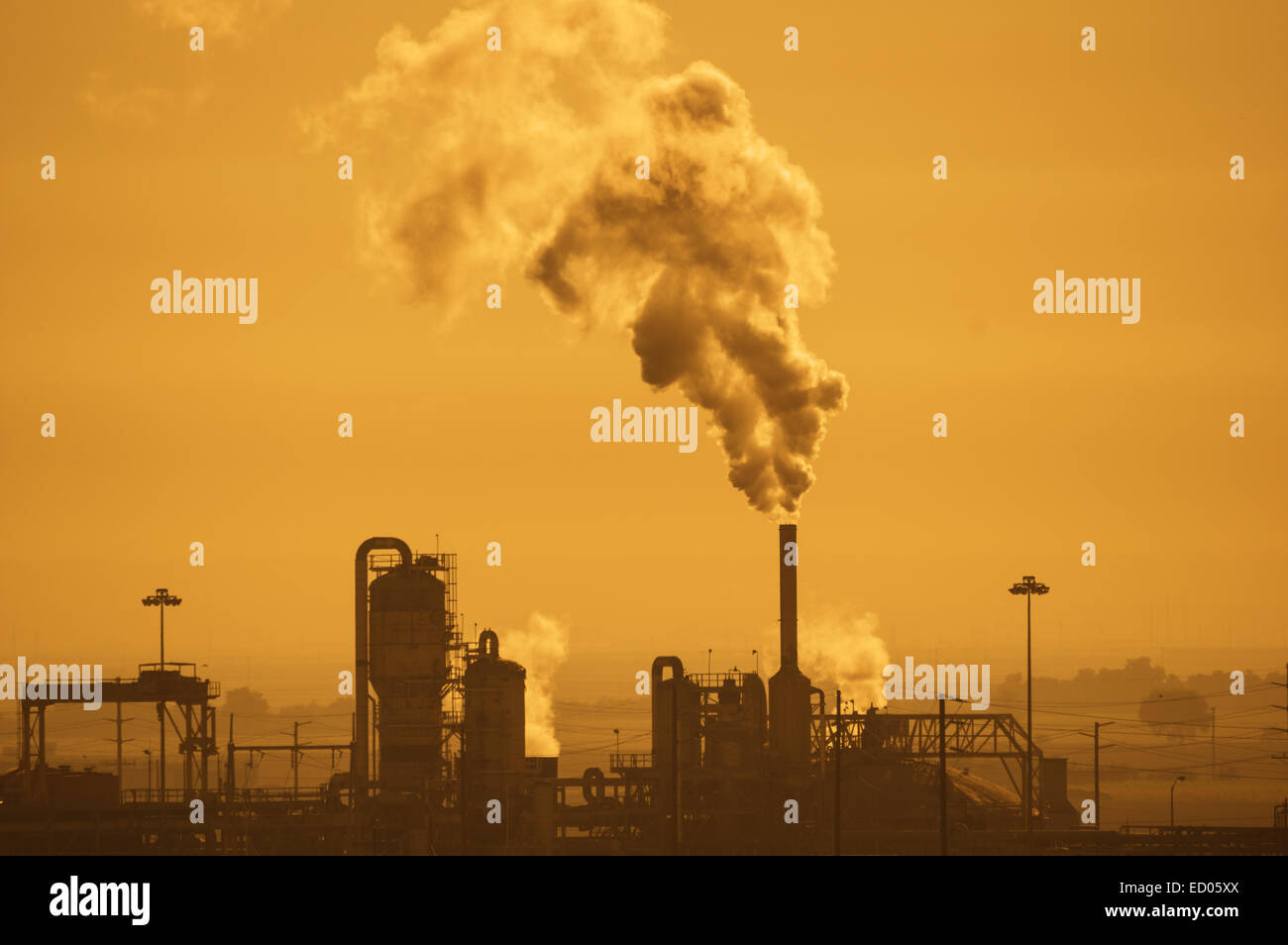 Industrieanlage mit Luftverschmutzung in einem dunstigen orangefarbenen Himmel Stockfoto