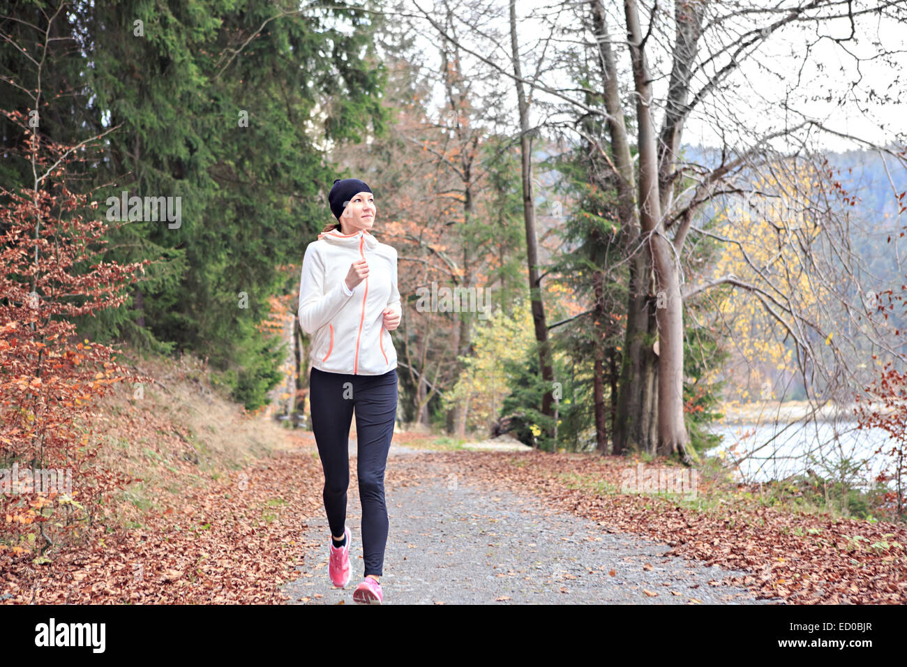 Frau läuft durch den Wald am See Stockfoto