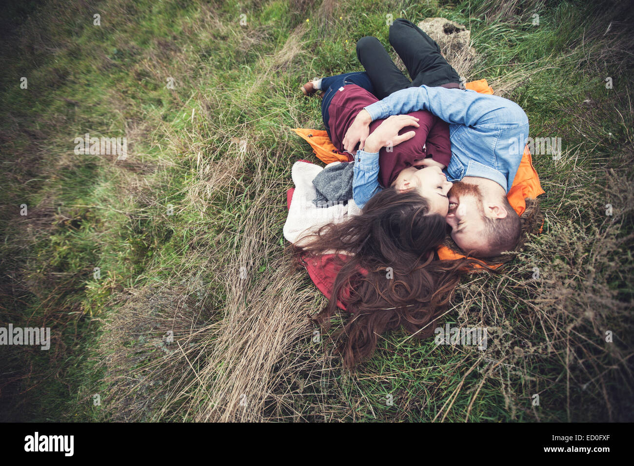 Junges Paar auf dem Rasen liegend und umarmt Stockfoto