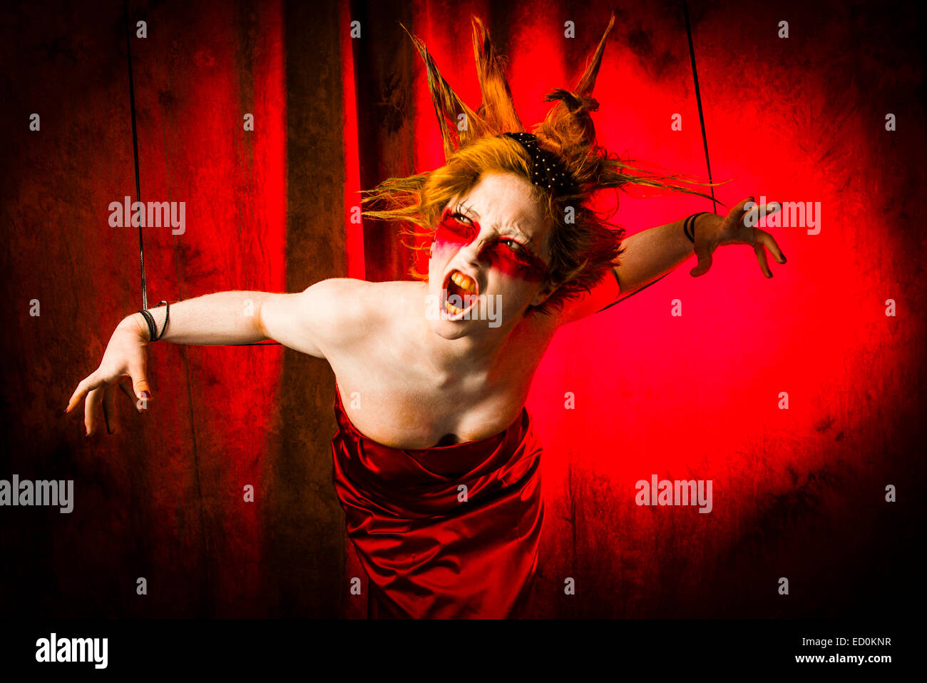 Fantasy-Verjüngungskur Fotografie - Seven Deadly Sins - Zorn: eine junge Frau-Mädchen-Modell mit stacheligen Punky Haar gebildet um zu schauen wie White-faced bemalte Puppe Porzellan und posiert wie eine Puppe in einem Fotostudio trägt eine rotes Kleid Kleid Ballkleid Stockfoto