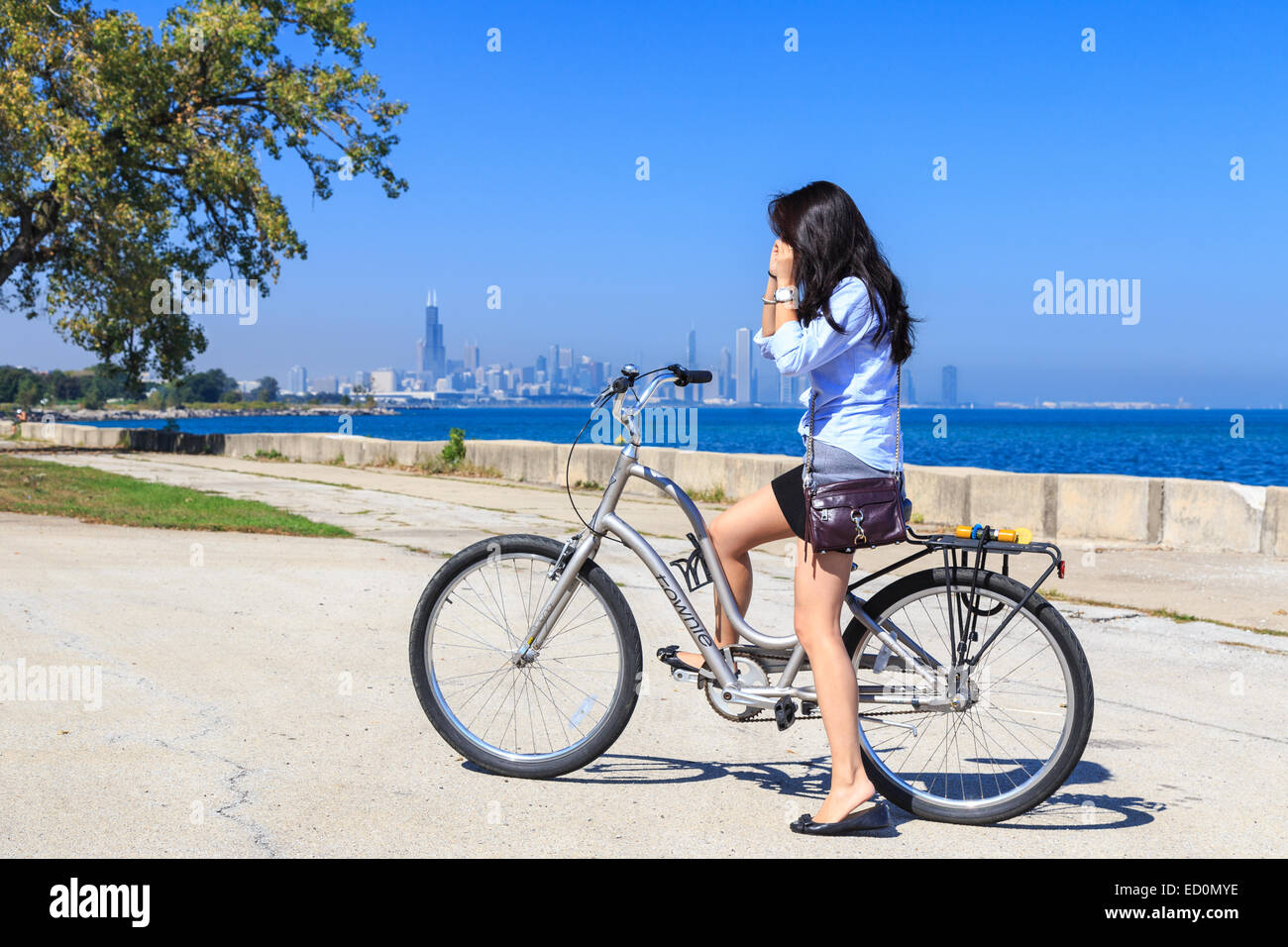Mädchen auf dem Fahrrad vor der Ferne Skyline von Chicago am Lake Michigan. Stockfoto