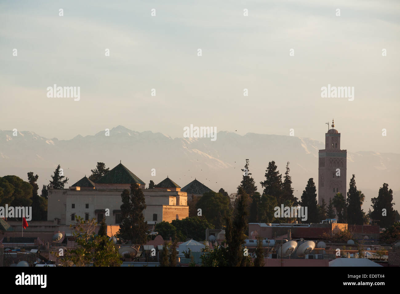 Blick auf die Skyline mit dem Minarett der Koutoubia-Moschee in der Dämmerung mit dem Atlas-Gebirge jenseits Stockfoto