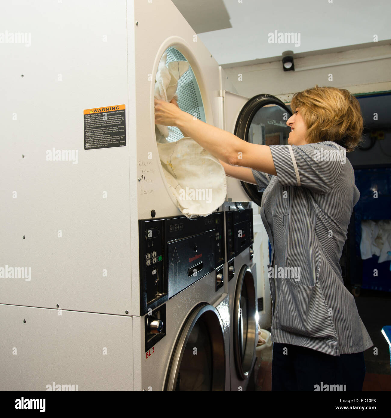 Eine Frau arbeiten laden Kleidung in industriellen Größe Wäschetrockner  Trockner in der Waschküche in einem Hotel, UK Stockfotografie - Alamy