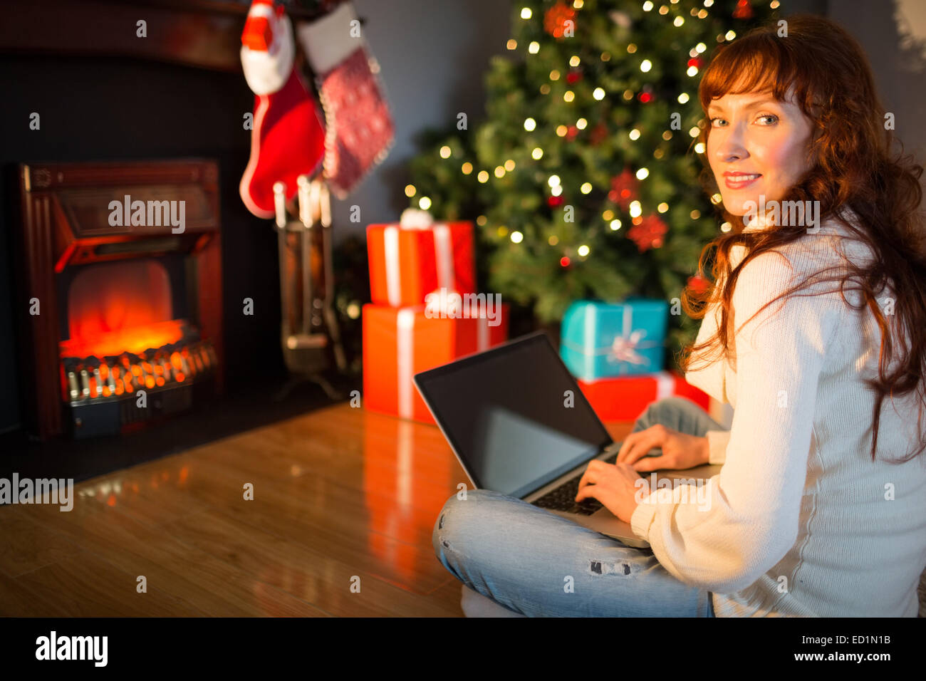 Rothaarige Frau sitzt am Boden mit Laptop zu Weihnachten Stockfoto