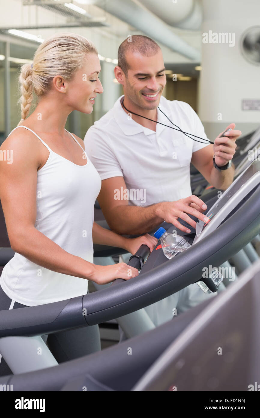 Männlichen Trainer timing seines Mandanten auf Laufband im Fitnessstudio Stockfoto