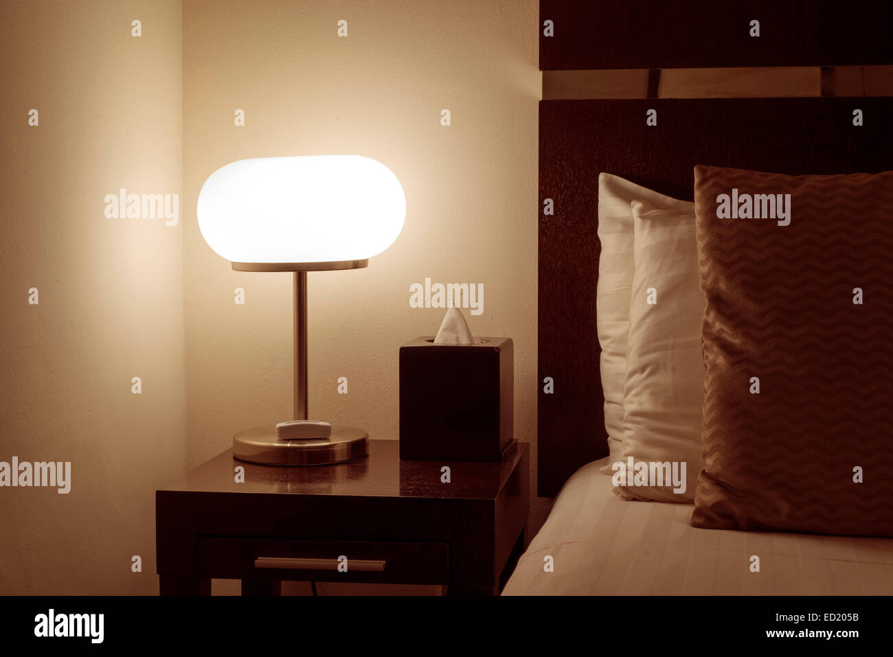 Hotel Zimmer Interieur mit beleuchteten Bett Licht auf Holztisch Stockfoto