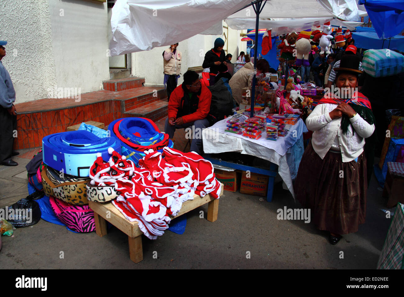 La Paz, Bolivien, 24. Dezember 2014. Ein Aymara-Frau oder Cholita tragen Tracht Spaziergänge vorbei an einem Stall zu verkaufen Santa Claus Hundemäntel in einen Weihnachtsmarkt. Bildnachweis: James Brunker / Alamy Live News Stockfoto