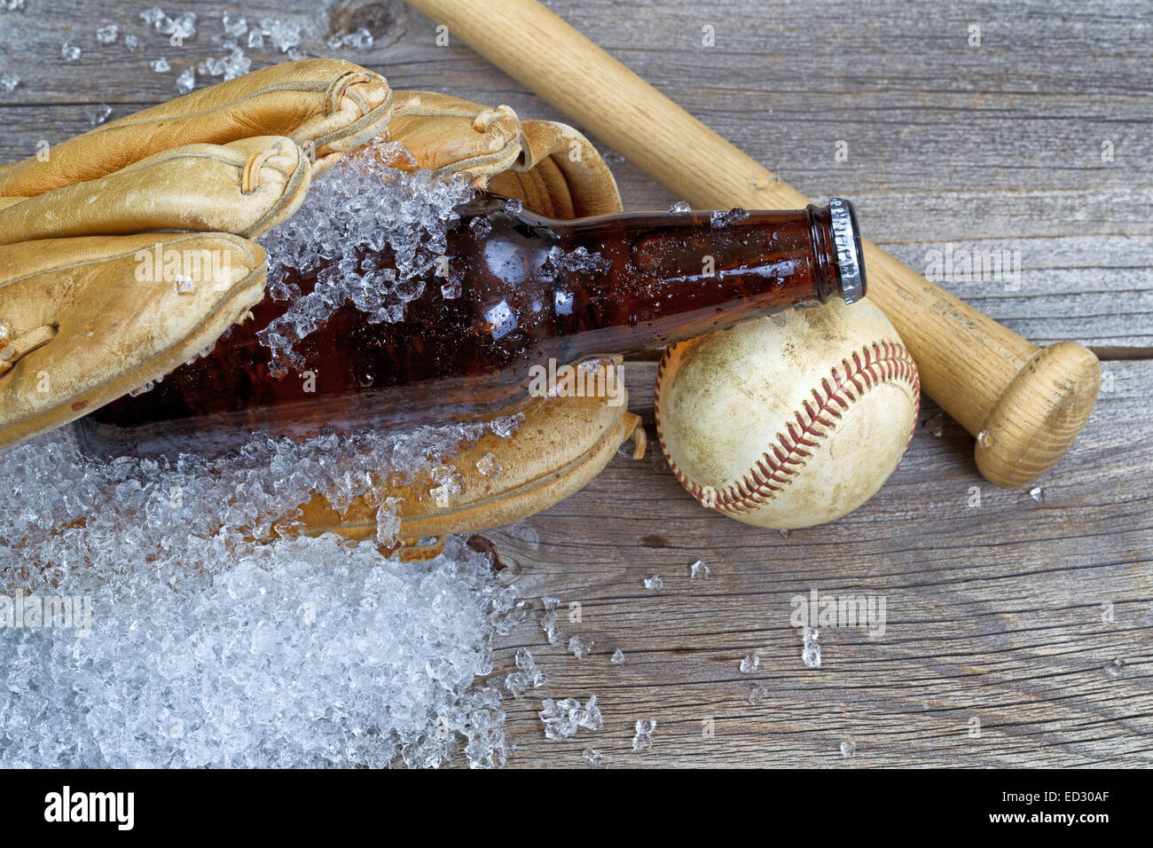 Nahaufnahme von einem braunen Flaschenbier mit crushed Ice in Baseball-Handschuh auf rustikalen Holz mit Ball und Schläger Stockfoto