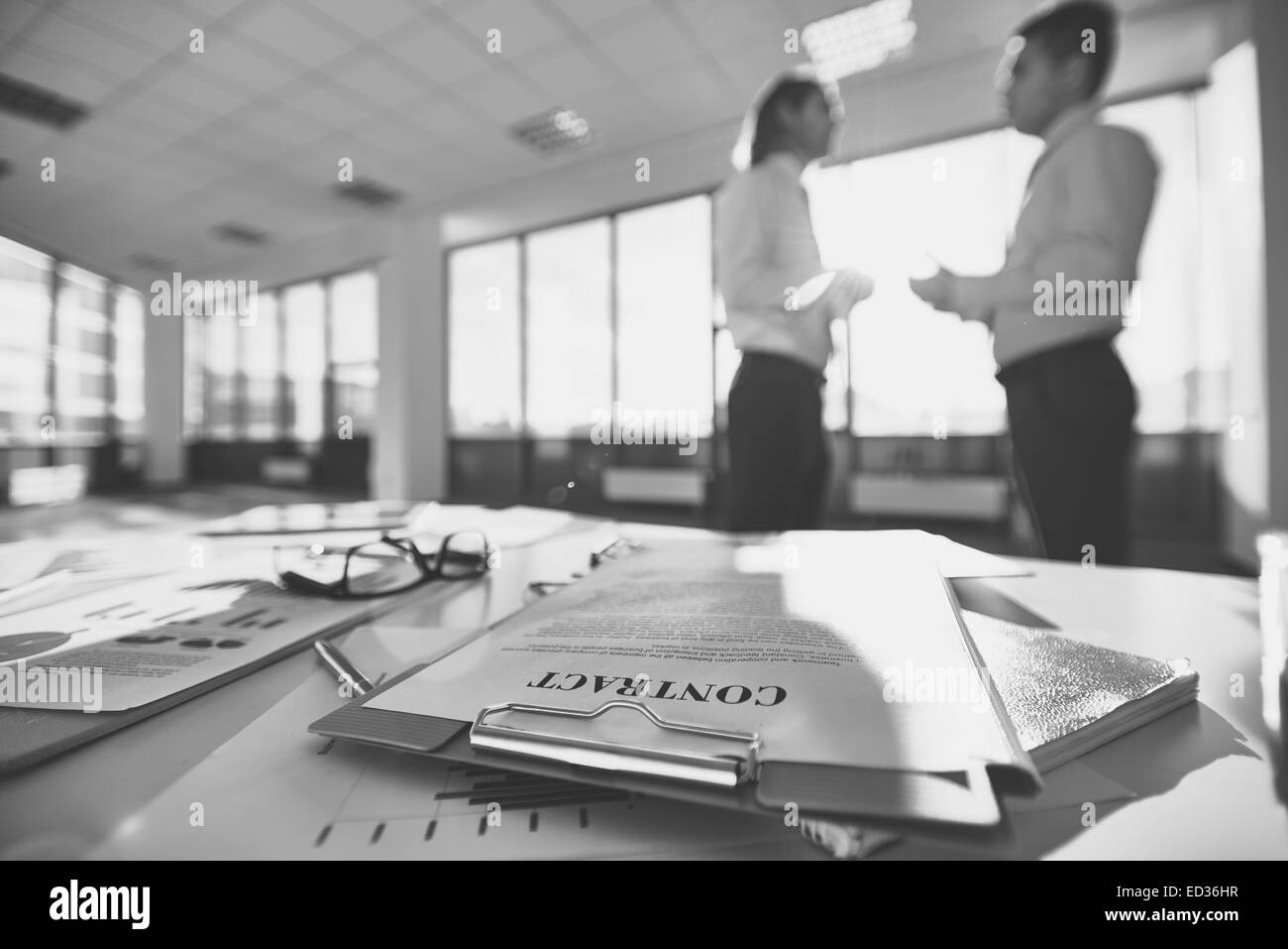 Geschäfts-Ausstattung auf den Schreibtisch und zwei Männer, die Kommunikation auf Hintergrund Stockfoto