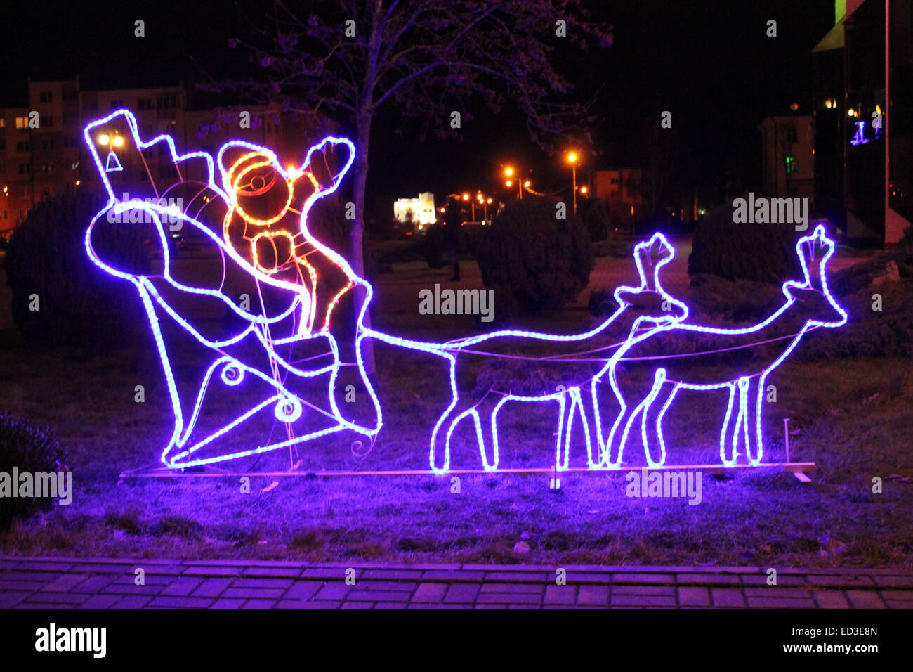 violette Lichtinstallation Weihnachtsmann im Schlitten mit Hirschen fahren am Abend Straße Stockfoto