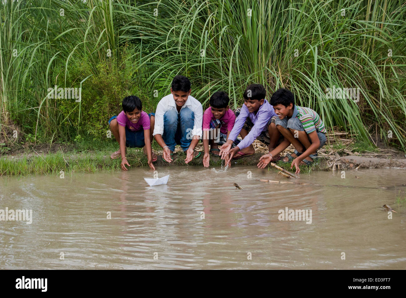 indische ländlichen Kinder jungen Teich spielen Papierschiff Stockfoto