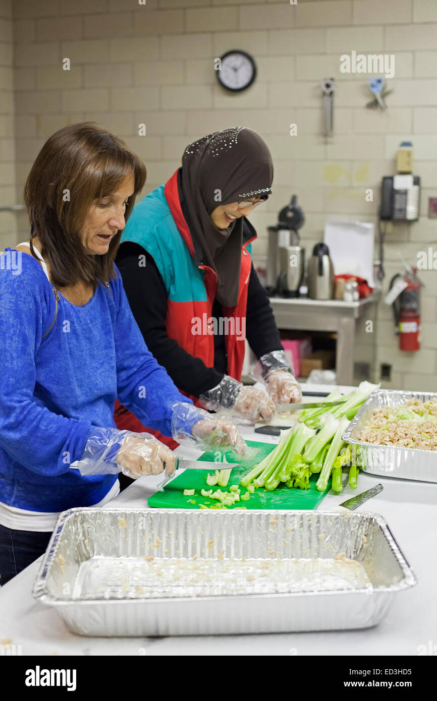 Oak Park, Michigan, USA - 25. Dezember 2014 - jüdischen und muslimischen Freiwilligen Kochen Weihnachten für Obdachlose in Gemeinde Beth Shalom als Teil des "Mizwa Day." Mizwa Tag geworden eine Weihnachtstradition in der Gegend von Detroit, wie Juden, Muslime, vor kurzem gesellte bei sozial Serviceagenturen freiwilliger. Debbie Landau (links) und Zenobia Lee gehackte Sellerie für Thunfischsalat. Bildnachweis: Jim West/Alamy Live-Nachrichten Stockfoto