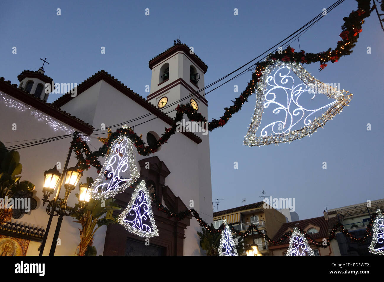 Weihnachtsdekoration Lichter, Glocken mit Kirche hinter Fuengirola, Andalusien, Spanien. Stockfoto