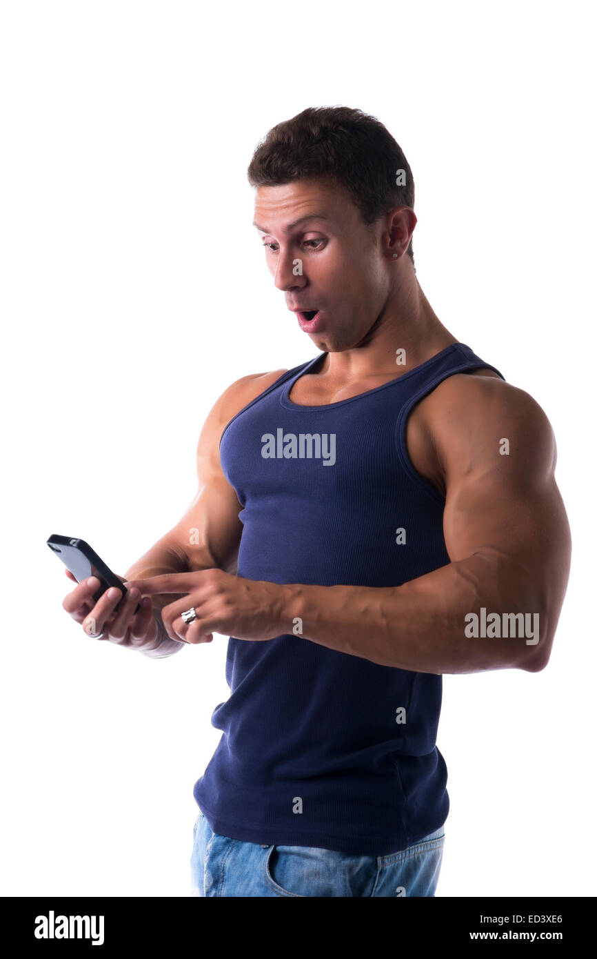 Schön passen muskulösen jungen Mann unter Schock, eine Handy-SMS-Nachricht zu reagieren, wie er aussieht, das Telefon in der Hand mit Stockfoto
