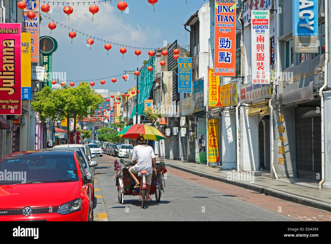 Fahrradrikscha / Beca mit Regenschirm Reiten durch die Einkaufsstraße in der Stadt George Town / Georgetown, Penang, Malaysia Stockfoto