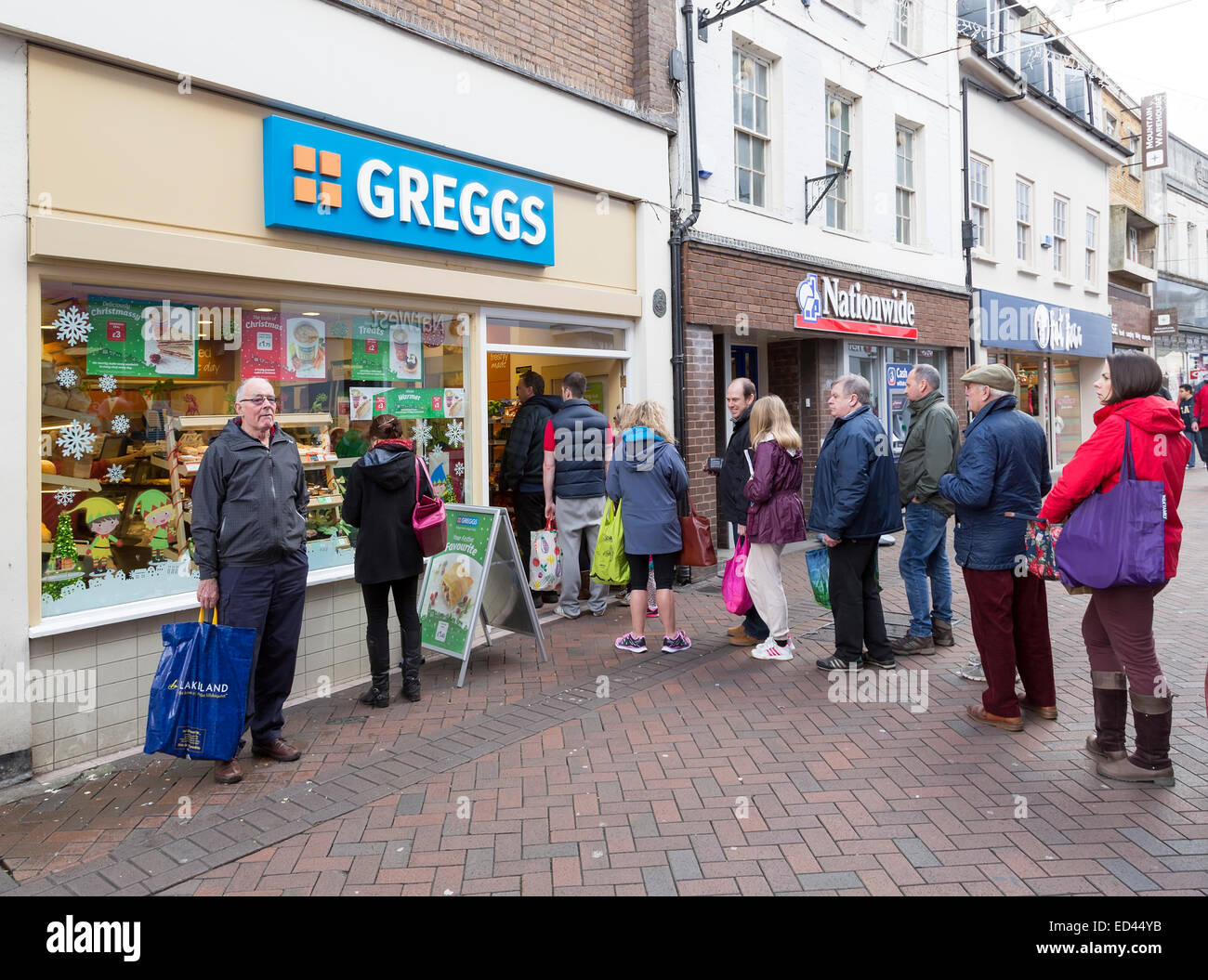 Die Warteschlange draußen Greggs Bäcker, Abergavenny, Wales, UK Stockfoto