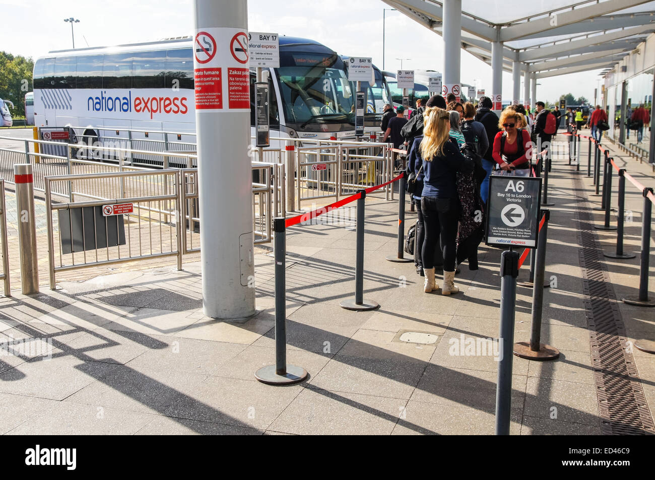 Reisende warten in einer Schlange vor dem Einsteigen in National Express Bus in London Stansted Flughafen Essex England Vereinigtes Königreich UK Stockfoto