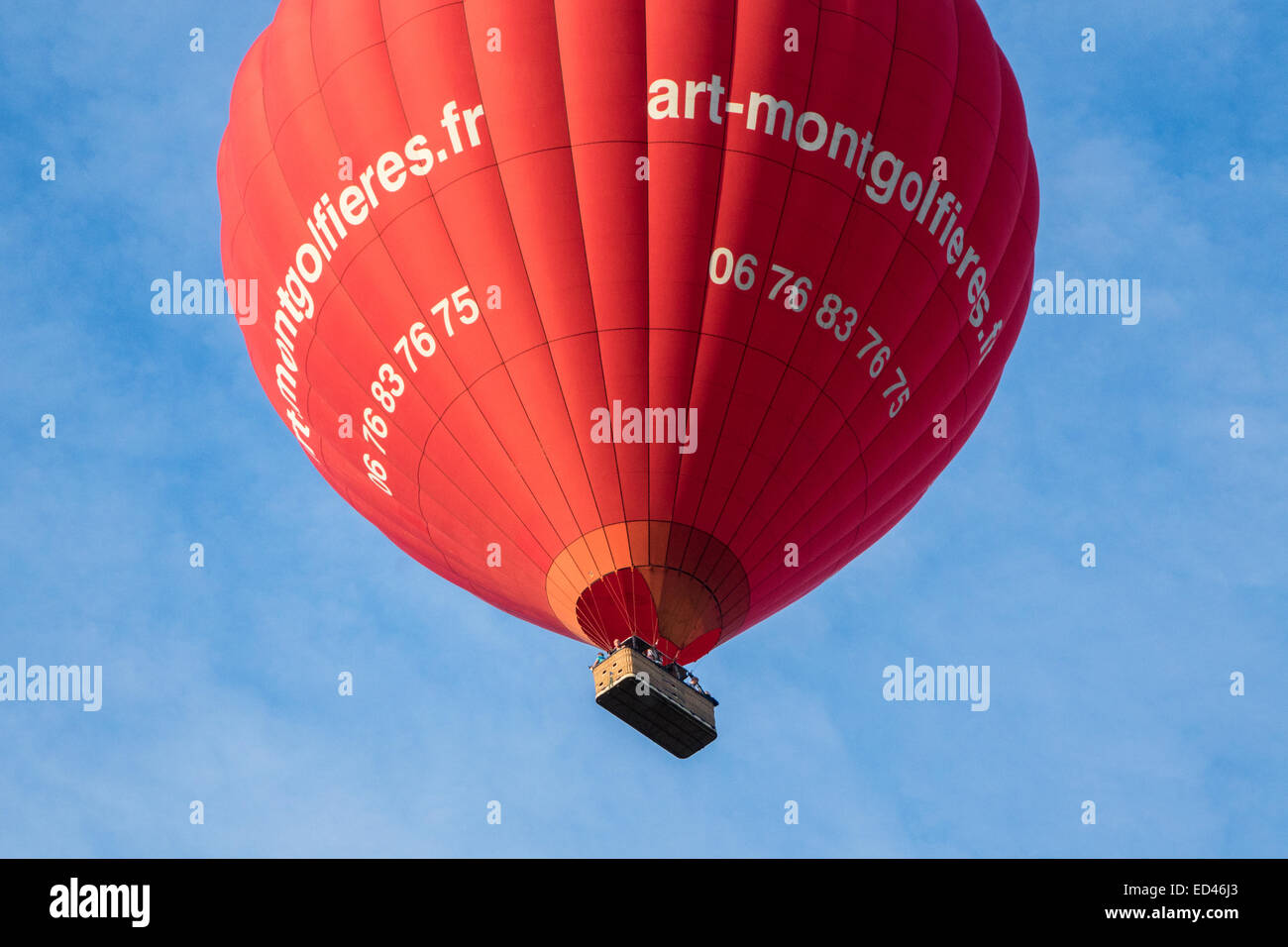 Roten Heißluftballon am blauen Himmel mit den Menschen in den Korb, Ansicht von unten Stockfoto