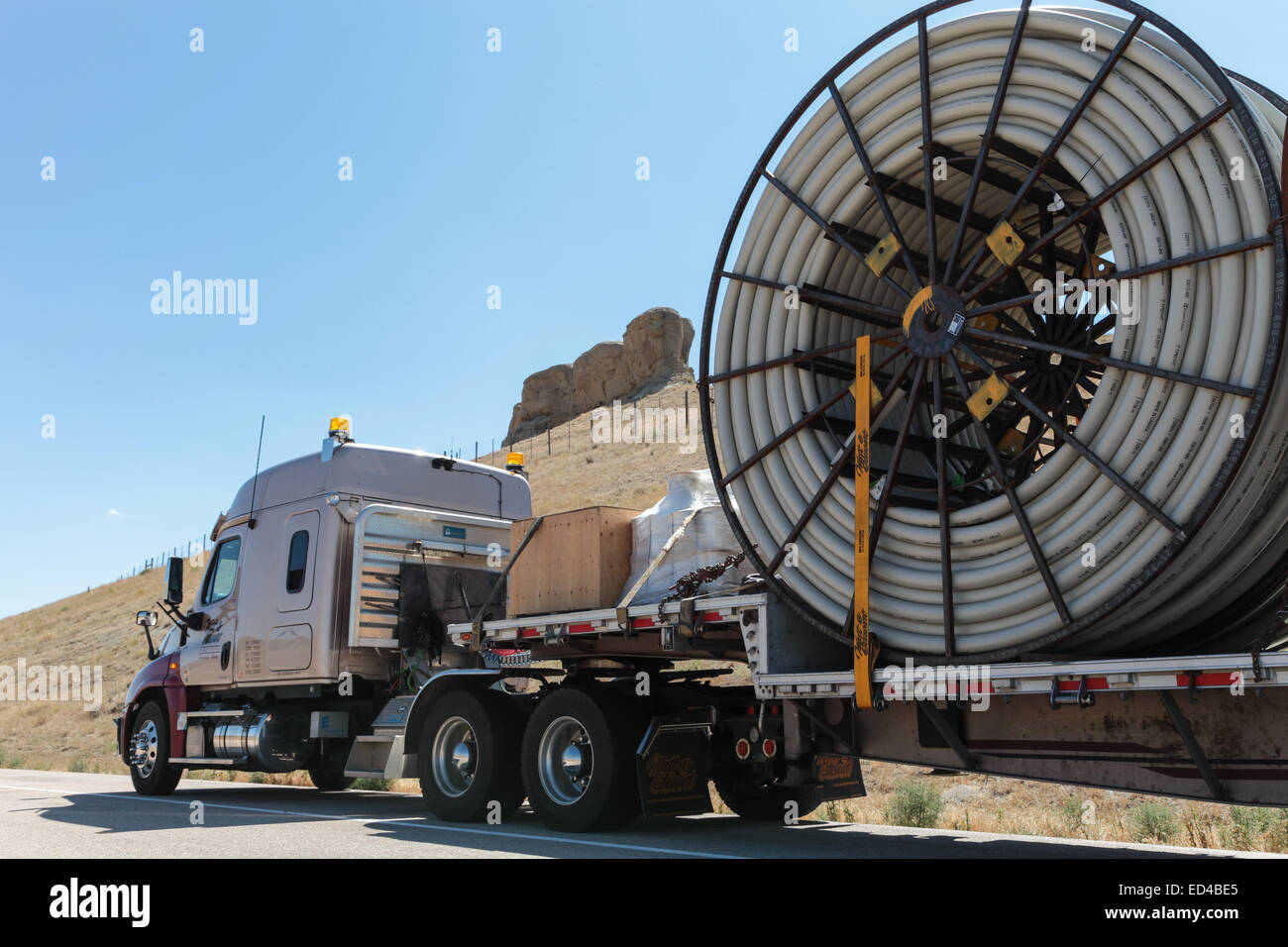 Eine amerikanische Semi Truck schleppen Rollen von HDPE-Kunststoff Rohr auf einem Tieflader für die Ölindustrie und fracking Standorten in den USA Stockfoto