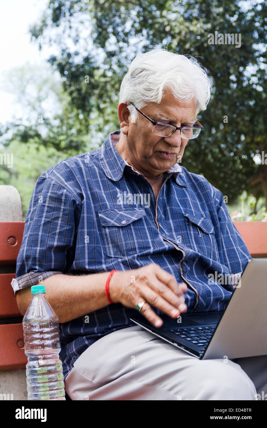 indische Greis Park Laptop arbeiten Stockfoto