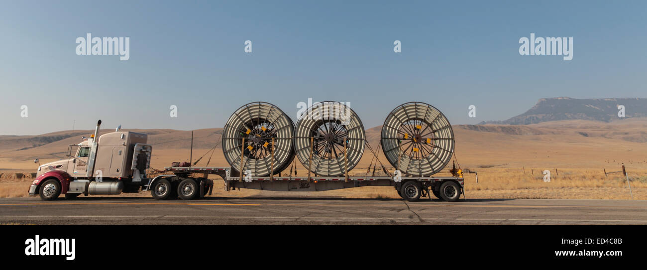 Eine amerikanische Peterbilt 379 Semi Truck schleppen Rollen von HDPE-Kunststoff Rohr auf einem Tieflader für die Ölindustrie und fracking Standorten in den USA Stockfoto