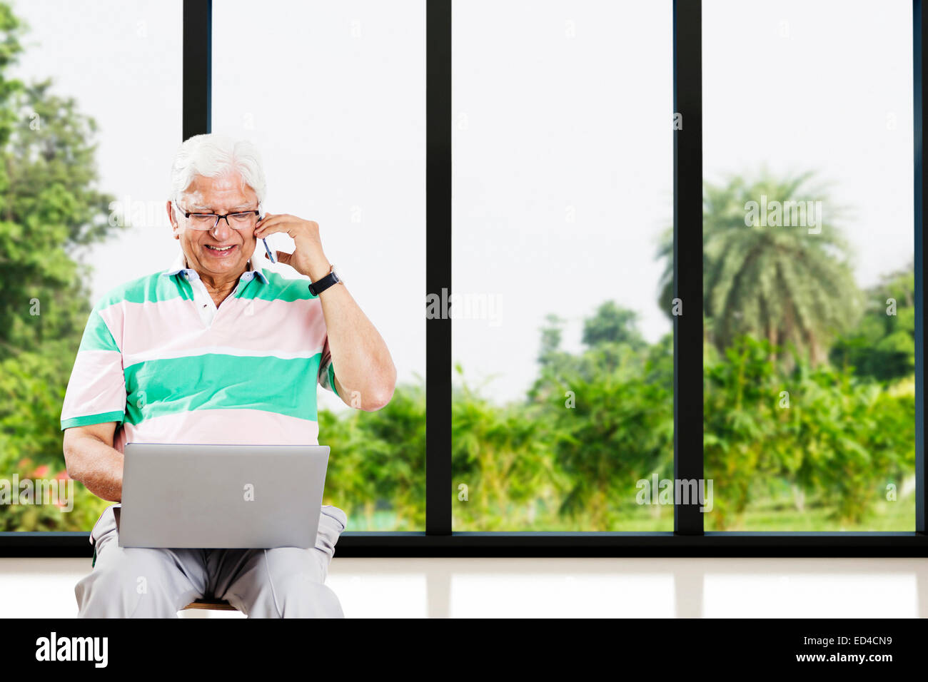 1 indische Greis Laptop und sprechende Telefon Stockfoto