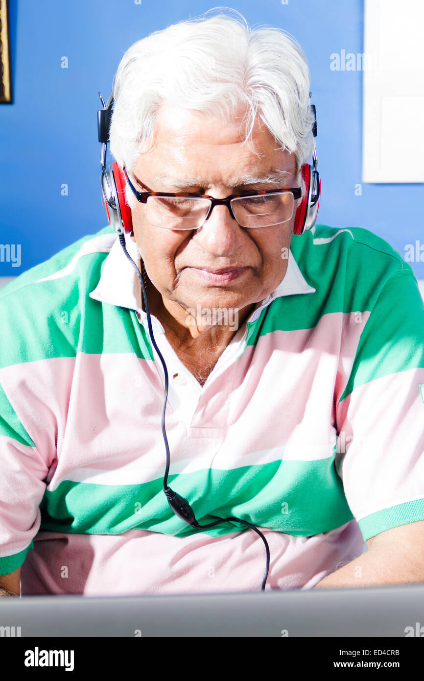 1 indische Greis Heimat Kopfhörer hören von Musik und Laptop arbeiten Stockfoto