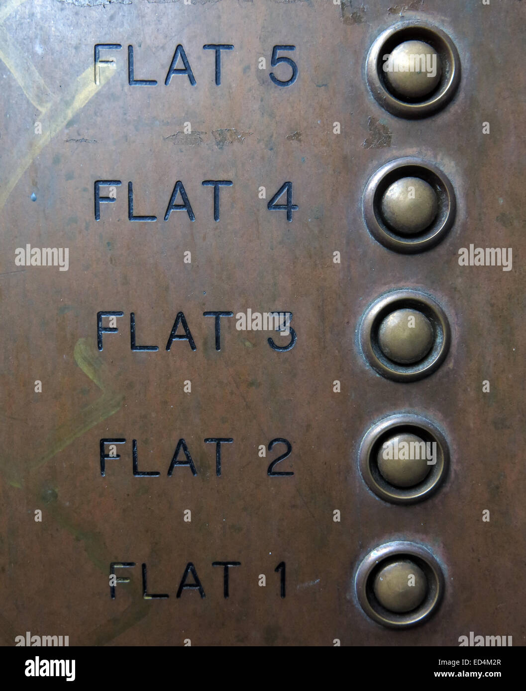 Eine Messingplatte mit Summern für Wohnungen 1 bis 5 mit Knöpfen verbunden mit Glocken Stockfoto