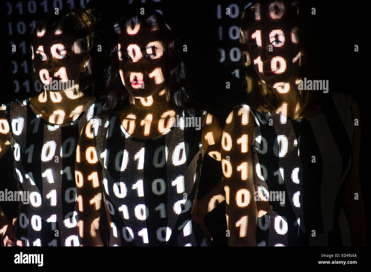 Digitale Kunst: Konzeptbild für Cyber-Terrorismus oder Cyber-Kriminalität Cyber-Kriminalität - eine Gruppe von 3 drei junge Frauen Mädchen mit ihren Gesichtern maskiert und verschleiert durch digitale Bitmap-Muster von binären Computer-Code auf ihren Gesichtern projiziert. Stockfoto