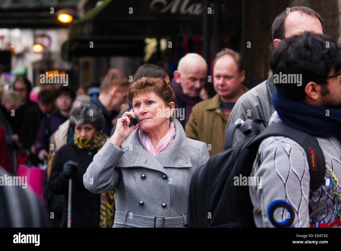 Finnsbury Park, London, 27. Dezember 2014. Alle Züge ein-und Kings Cross, einer der verkehrsreichsten Bahnhöfe in London, wurden dank Technikarbeit auf der East Coast mainline überrennen abgesagt. Eine begrenzte Sevice führt vom Finnsbury Park entfernt, die stark verstopft werden, mit British Transport Police gerufen, um die Kontrolle der Massen zu unterstützen. Bild: Eine Frau Schlangestehen vor Foinnsbury Park Station macht einen Anruf während der langen Wartezeit. Bildnachweis: Paul Davey/Alamy Live-Nachrichten Stockfoto