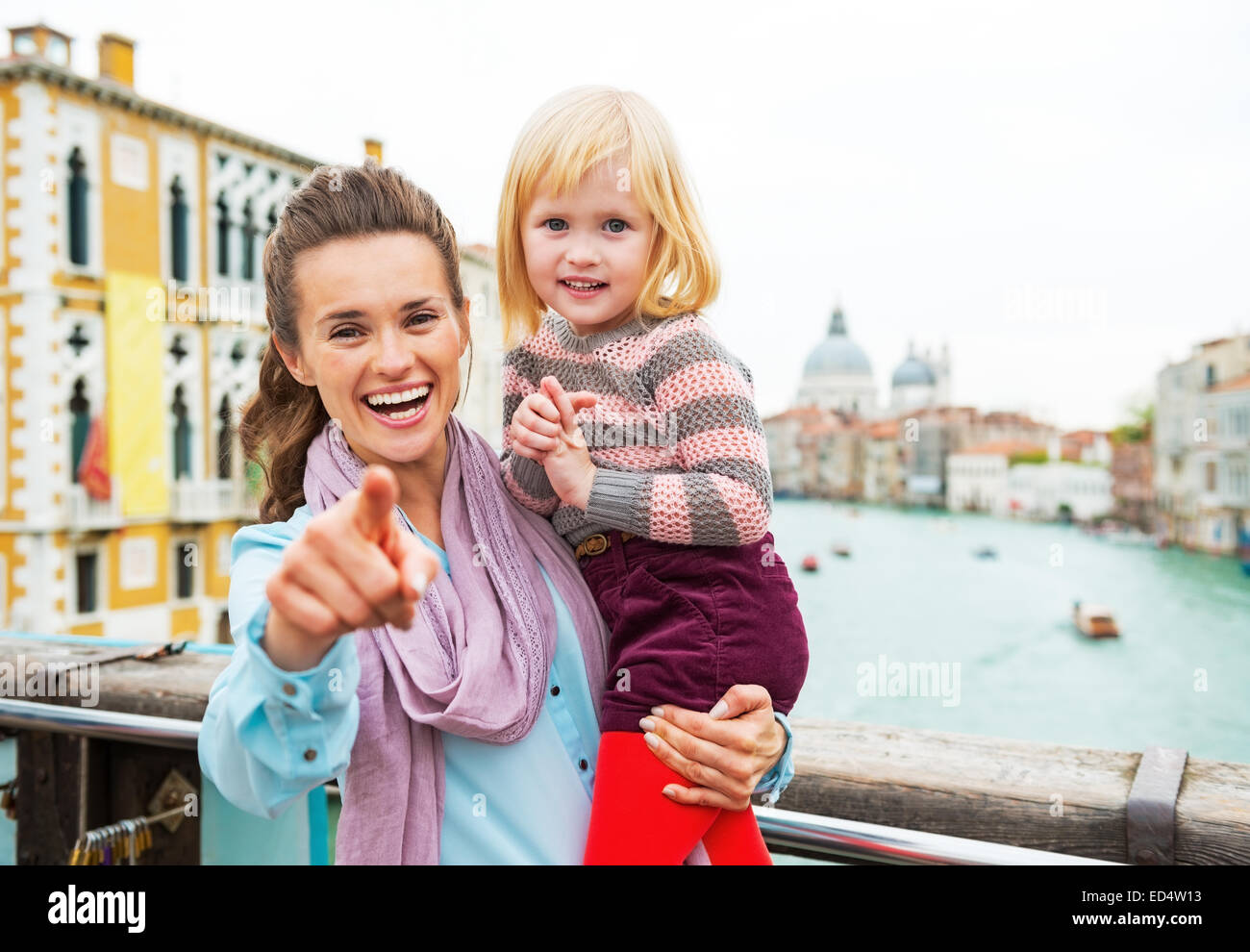 Baby Mädchen und Mutter deutete in der Kamera beim stehen auf der Brücke mit Blick auf Canale Grande in Venedig, Italien Stockfoto