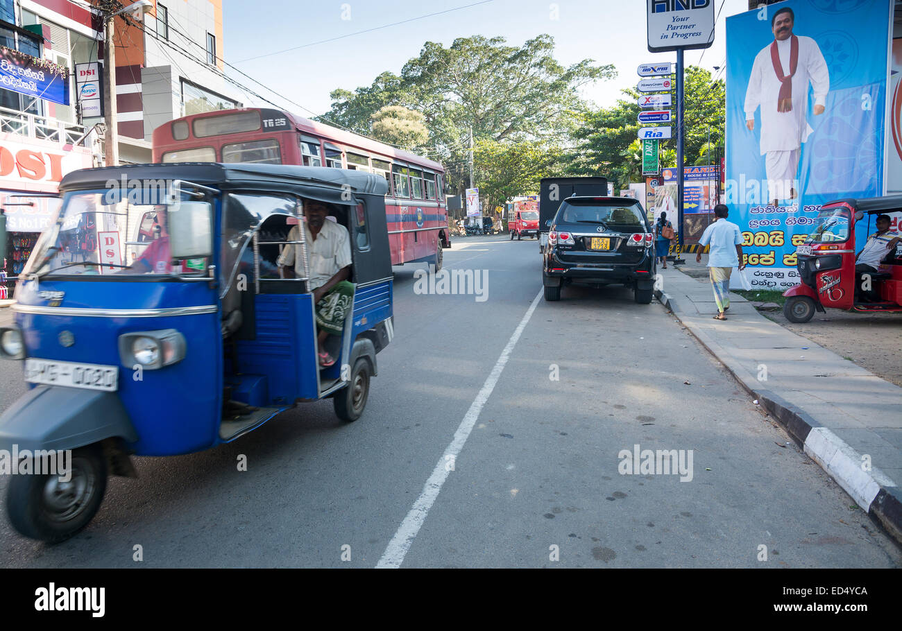 Straßenansicht mit Wahl Plakat Tuk Tuk Verkehr und Auto in Tangalle am 15. Dezember 2014 in Tangalle, Sri Lanka, Asien. Stockfoto