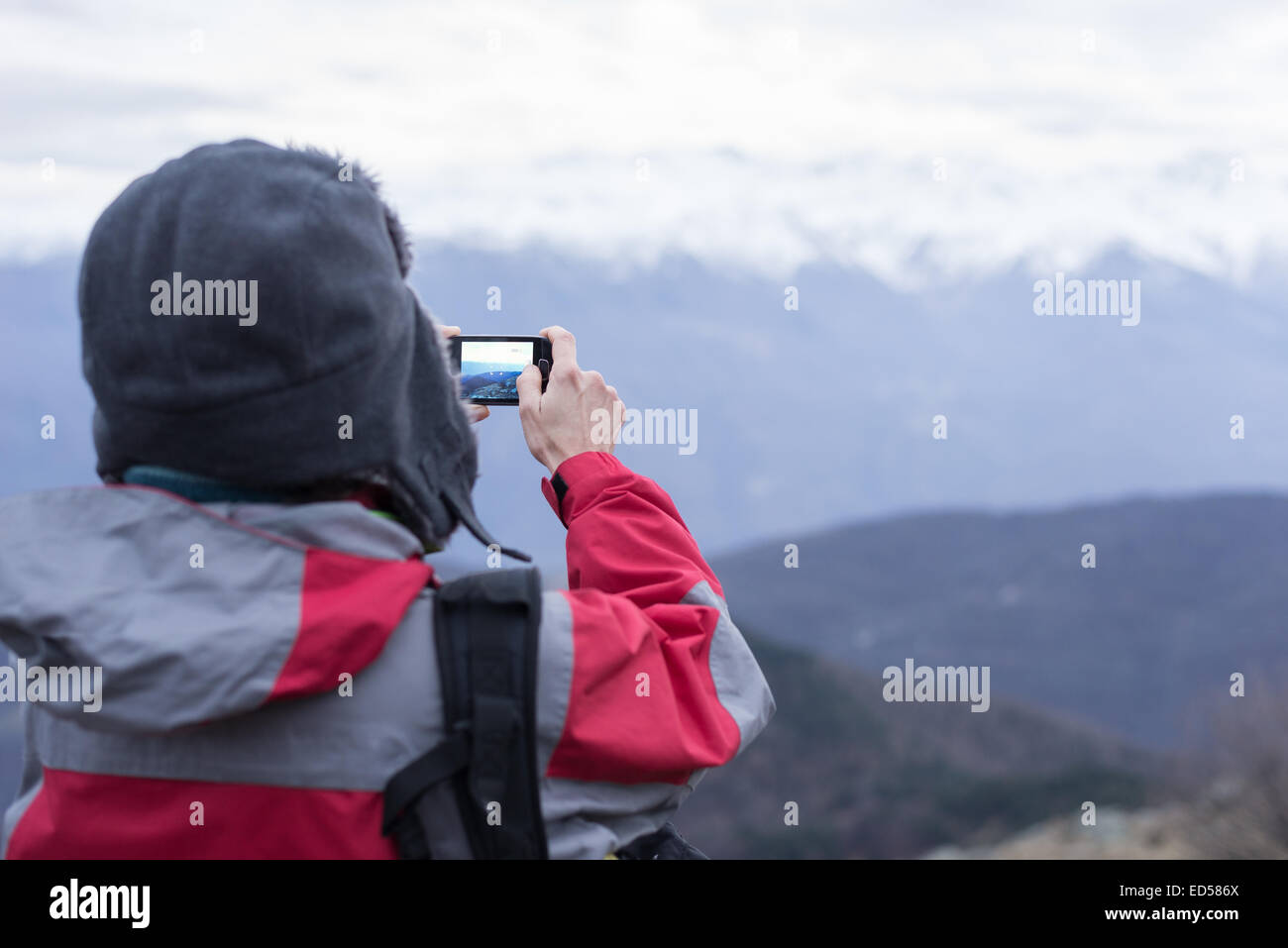 Wanderer unter Bild mit Telefon, das majestätische Panorama der italienischen Westalpen in der Wintersaison. Kältegefühl, selec Stockfoto