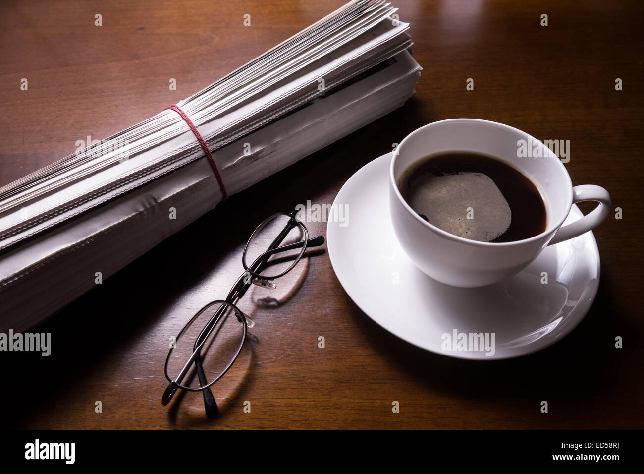 Zeitung, Gläser und Becher Kaffee am Schreibtisch Stockfoto