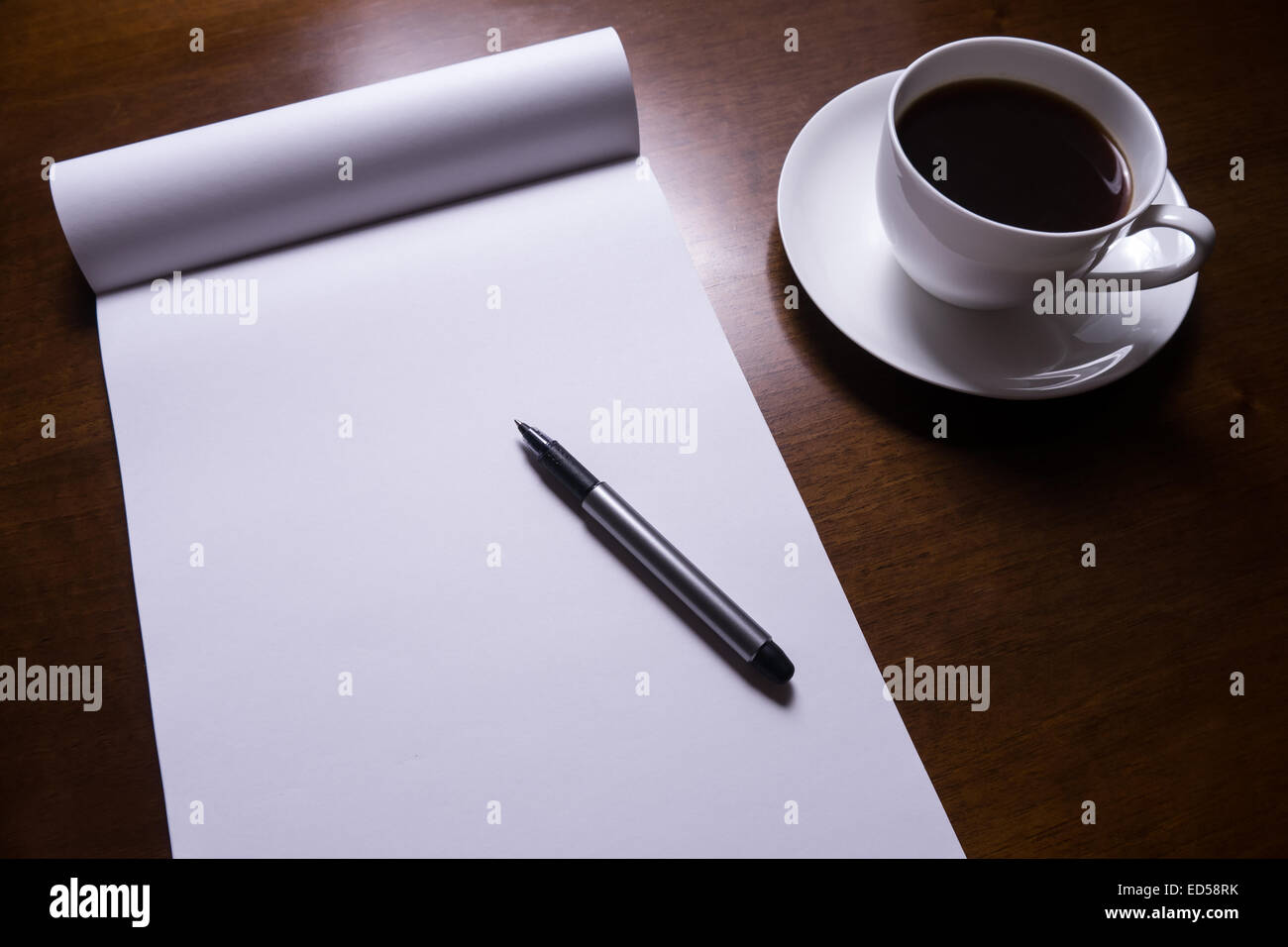 Blatt Papier, Stift und Tasse Kaffee am Schreibtisch Stockfoto