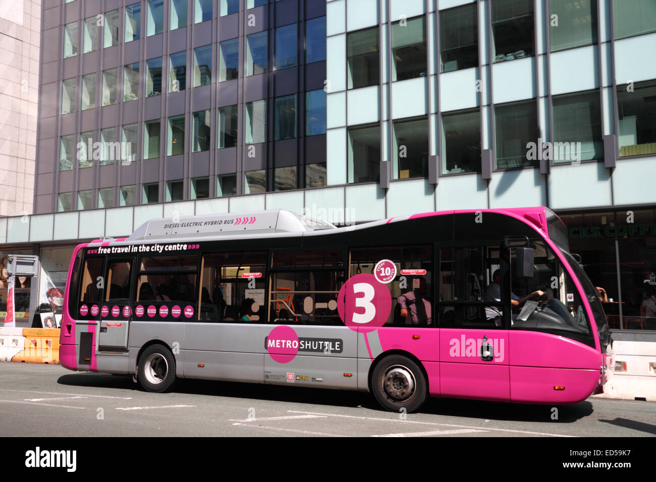 Ein rosa und grauen Hybrid-Diesel und Elektro "Bus neben einem modernen Bürogebäude in Manchester. Stockfoto