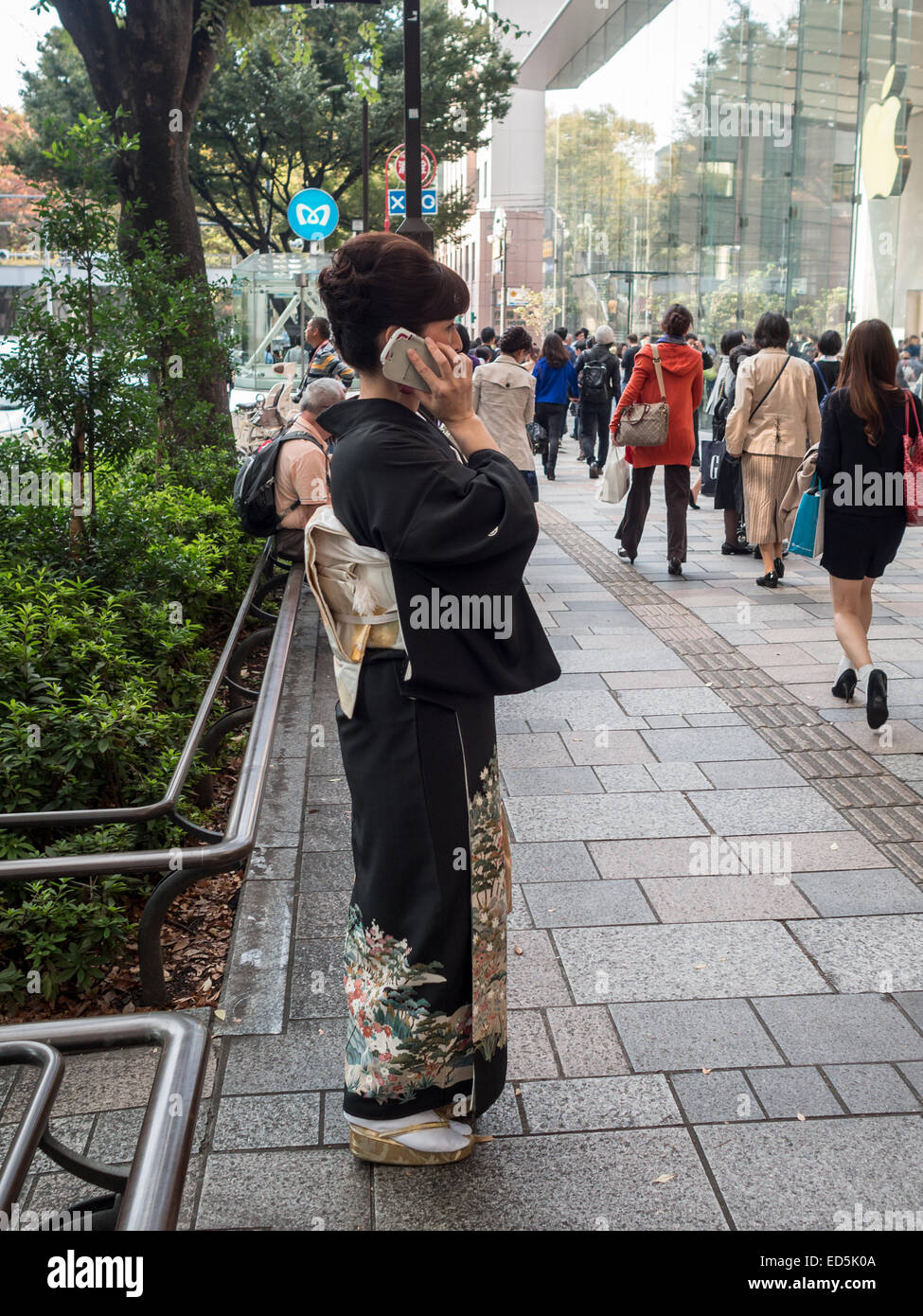 Frau im traditionellen japanischen Kostüm am Telefon auf der Straße Stockfoto