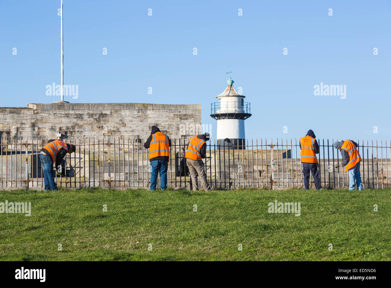 Straftäter in Southsea Castle, Portsmouth, Durchführung gemeinnütziger Arbeit; Orange Jacken eingeschrieben "Gemeinschaft Payback" Stockfoto