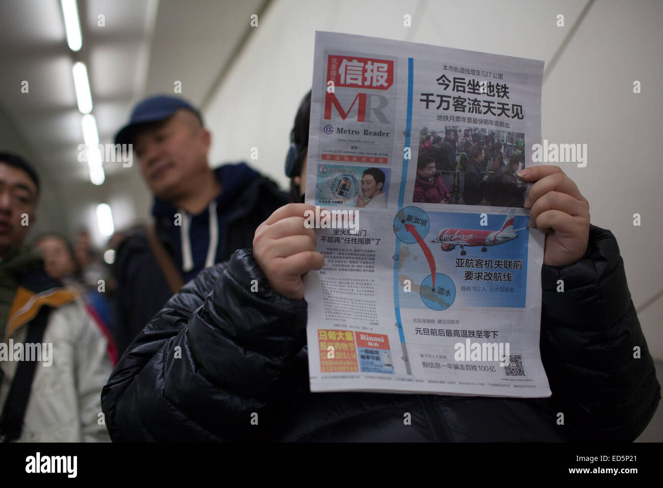 Peking, China. 29. Dezember 2014. Ein Passagier liest Zeitung an u-Bahnstation Guomao in Peking, China, 29. Dezember 2014. Die öffentliche Verkehrsmittel in Peking verabschiedeten neuen Tarife am 28. Dezember die bisherigen Preise im Durchschnitt doppelt, aber die Preissteigerung hört nicht Pendler, die fern von ihrer Arbeit von der Auswahl der öffentlichen Verkehrsmittel, insbesondere u-Bahn. © Jin Liwang/Xinhua/Alamy Live-Nachrichten Stockfoto