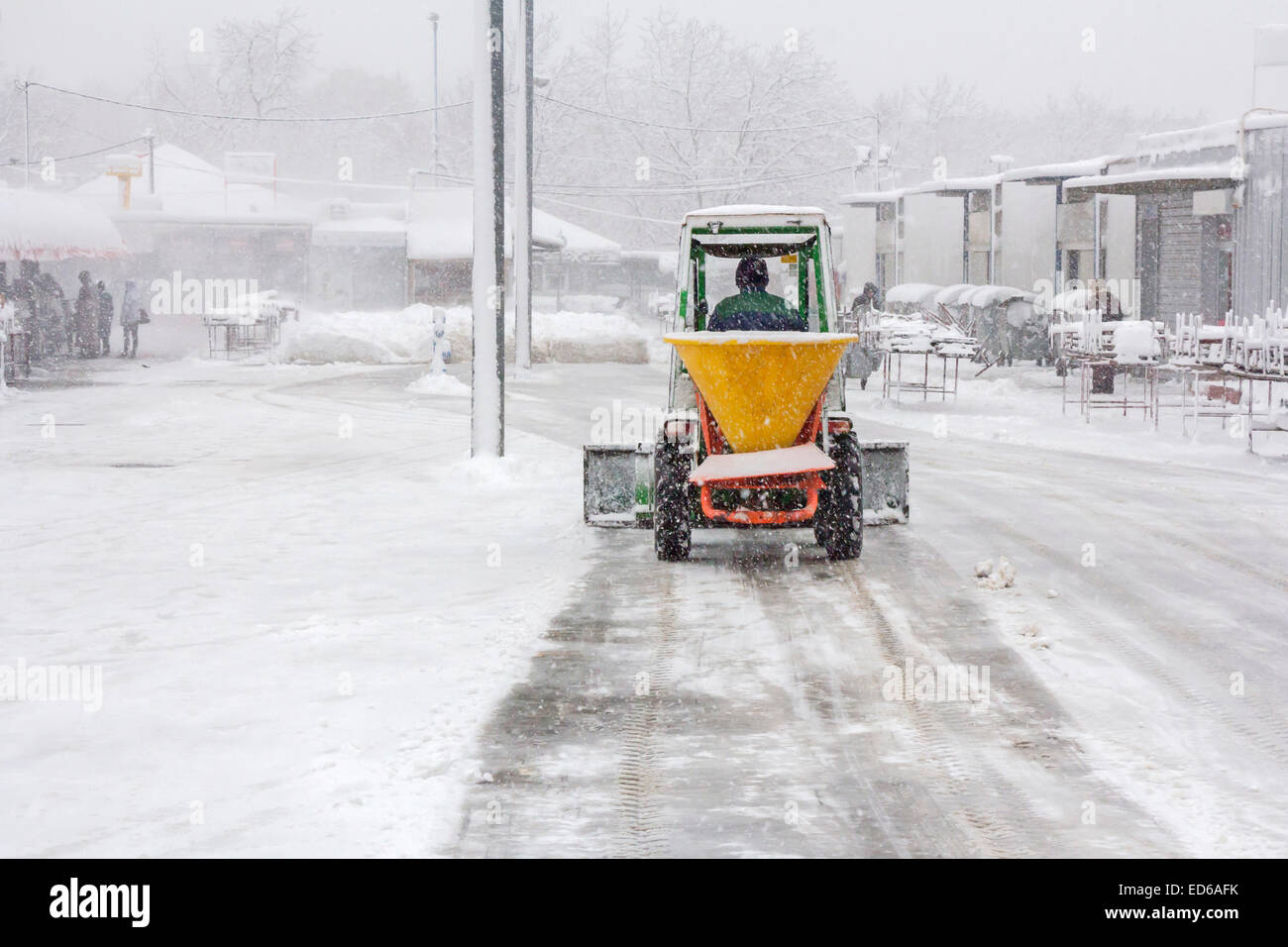 Kleines schneeräumfahrzeug, das schnee auf dem stadtplatz entfernt gelber  oder orangefarbener traktor, der den schnee reinigt